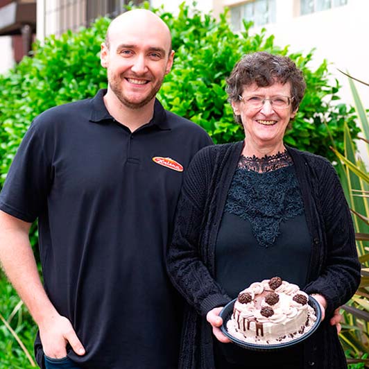 Maria Helena Bertin segurando a torta ao lado do Cassiano Bertin, ambos da Confeitaria Helena