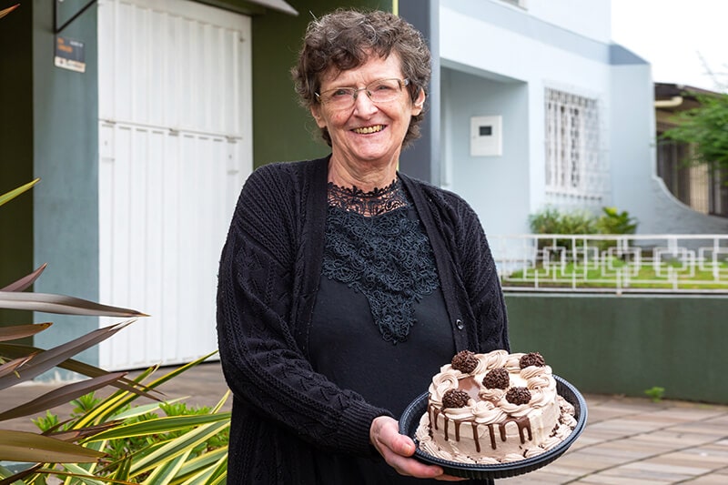 Maria Helena segurando a torta doce da Confeitaria Helena