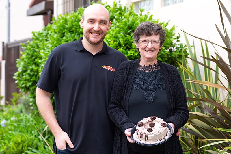 Maria Helena Bertin segurando a torta ao lado do Cassiano Bertin, ambos da Confeitaria Helena