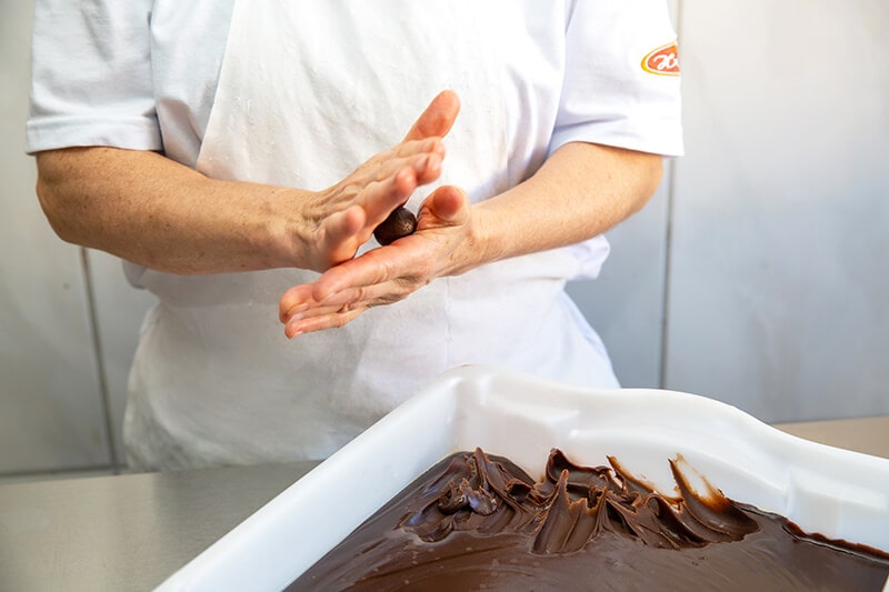 Mulher enrolando os docinhos da Confeitaria Helena