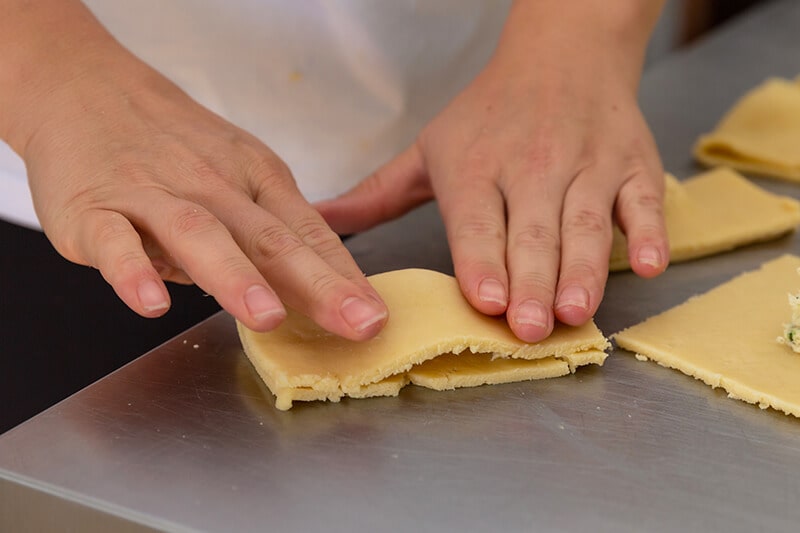 Mulher fechando os pastéis da Confeitaria Helena