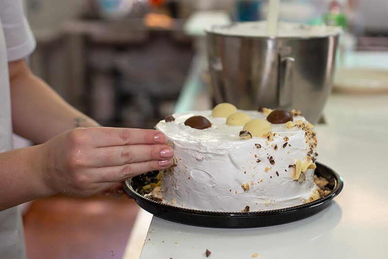 Mulher finalizando o acabamento da torta doce da Confeitaria Helena