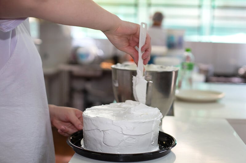 Mulher finalizando o acabamento da torta da Confeitaria Helena
