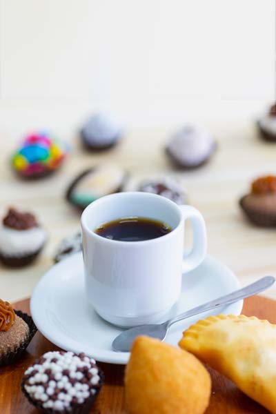 Docinhos e salgados com uma xícara de café da Confeitaria Helena