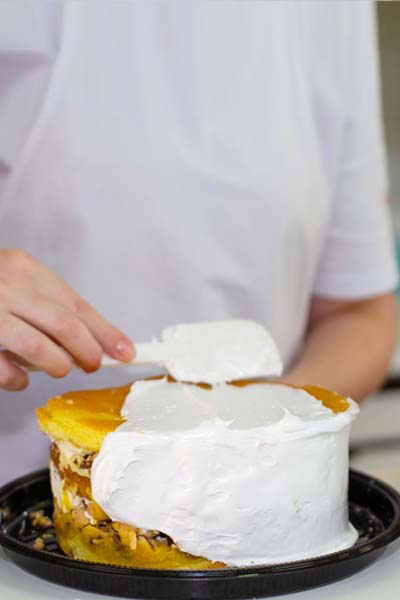 Mulher decorando a Torta Doce com Glacê da Confeitaria Helena