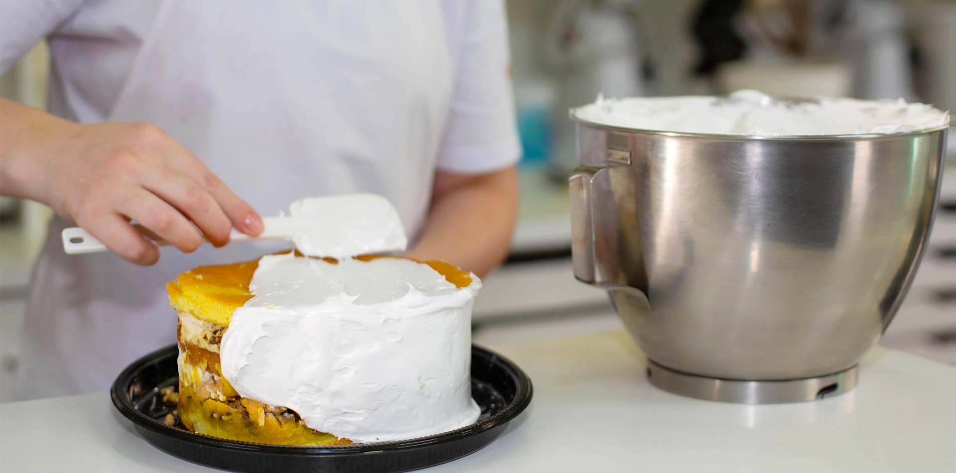 Mulher decorando a Torta Doce com Glacê da Confeitaria Helena